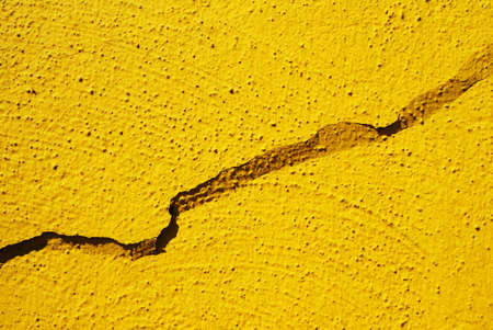 Cracked painting on a yellow wallの写真素材