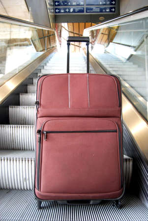 Suitcase lifted up on an escalatorの写真素材