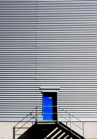 Silver cladding and a blue door in a factoryの写真素材