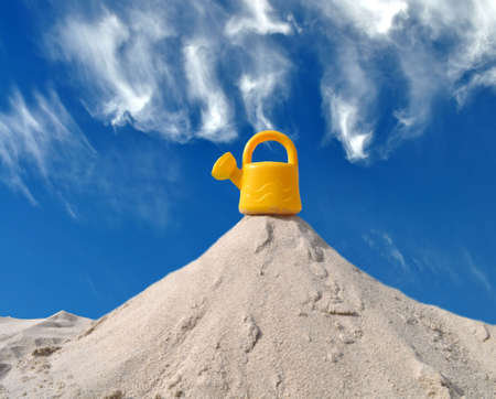 Yellow watering toy can on a sand hillの写真素材