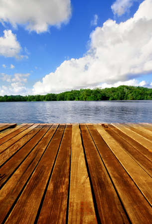 Wooden brown boardwalk on a lake with blue sky and cloudsの写真素材