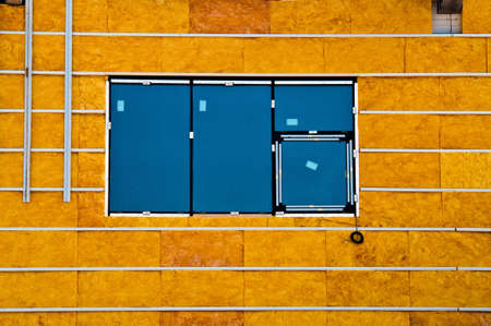 Blue window and yellow insualtion material on a wallの写真素材