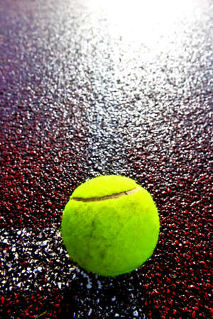 Tennis ball on a red court with backlightの写真素材