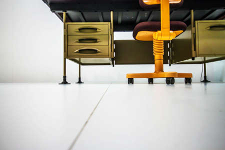 Old office table with chair seen from below on a white backgroundの写真素材