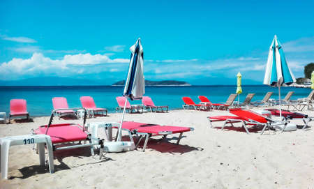 Parasol and red sundeck chairs on a white sand beach at an ocena beach in Greeceの写真素材