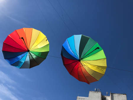 Colorful umbrellas in the air against a blue skyの写真素材