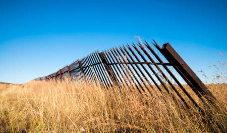 Metal fence and a grass landscape with blue skyの写真素材
