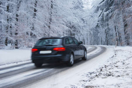 Black car on a curvy street in a winter forestの写真素材