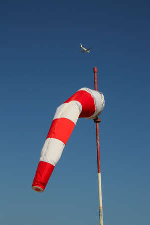 Red and white windsock with A320 aeroplane to the rear の写真素材