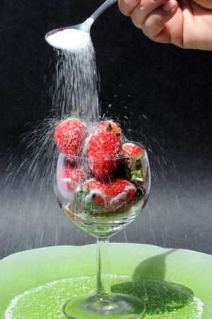 Sprinkling granulated sugar onto whole fresh strawberries の写真素材