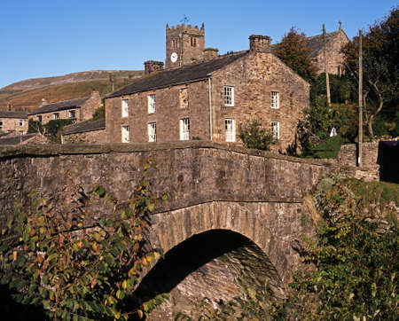 Stone road bridge over Straw Beck with village and church to rear, Muker, Swaledale, Yorkshire...