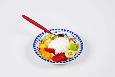 Bowl of fruit salad with yoghurt against a plain background の写真素材