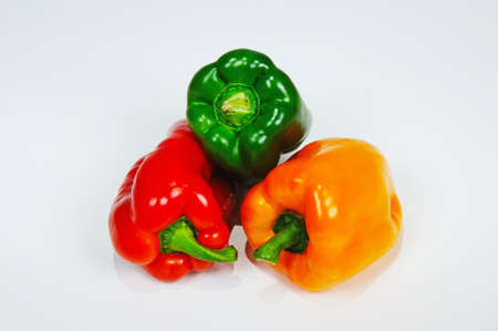 Red, Green, and Yellow Capsicums against a plain background の写真素材