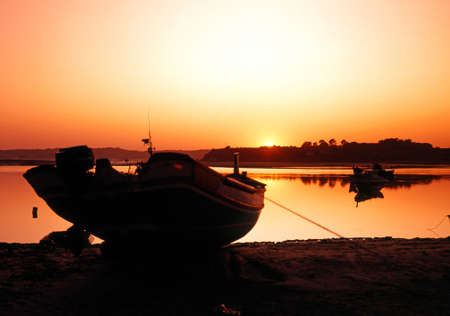 Fishing boat in harbour silhouetted against setting sun, Alvor, Algarve, Portugal, Western Europe の写真素材