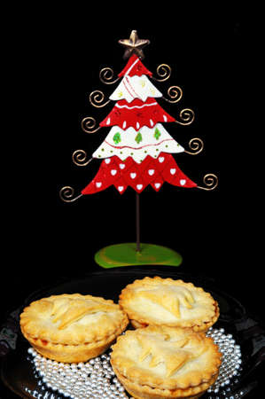 Three homemade mince pies surrounded by edible silver balls with a pretty tin Christmas tree to the rear, England, UK, Western Europe の写真素材