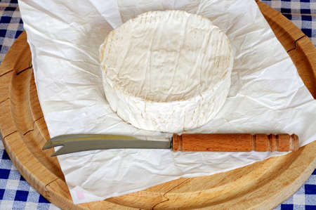 Whole French Camembert on a round wooden chopping board の写真素材