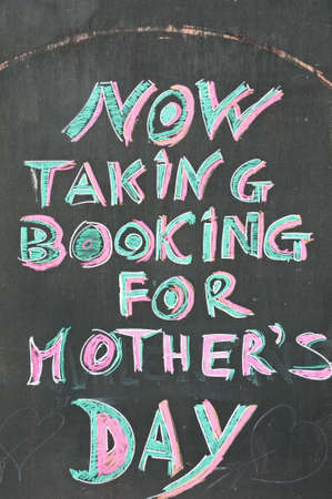 Now taking bookings for Mothers Day text written on chalkboardの写真素材