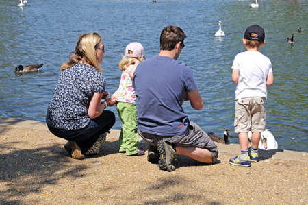 Stratford-upon-Avon, England - May 18, 2014 - Couple with two small children feeding the ducks and swans along the River Avon, Stratford-Upon-Avon, Warwickshire, England, Western Europe のeditorial素材
