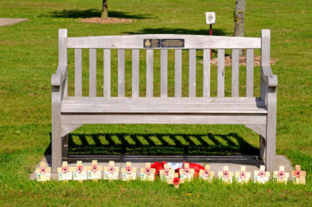 Alrewas, UK - May 21, 2014 - Wooden bench with poppy memorials at the base, National Memorial Arboretum, Alrewas, Staffordshire, England, UK, Western Europe のeditorial素材