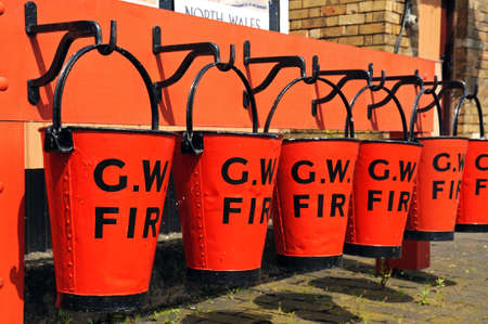 Row of red Victorian Fire buckets on the railway platform, Hampton Loade, Shropshire, England, UK, Western Europe の写真素材