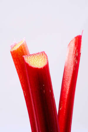 Three sticks of rhubarb against a plain background 