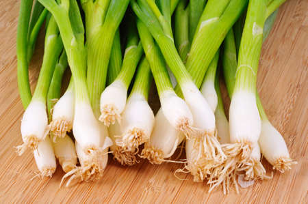 Bunch of white spring onions on a wooden chopping board の写真素材