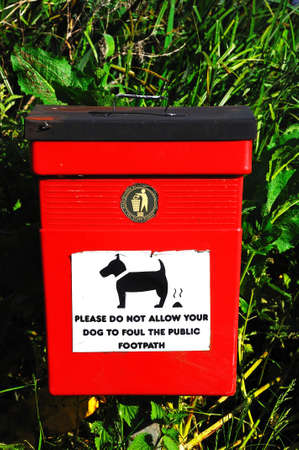 Red litter bin with a dog fouling message on the front, Barton-under-Needwood, Staffordshire,...