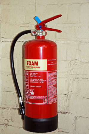 Derby, United Kingdom - July 17, 2014 - Red foam fire extinguisher against a brick wall, Derby, Derbyshire, England, UK, Western Europe.のeditorial素材
