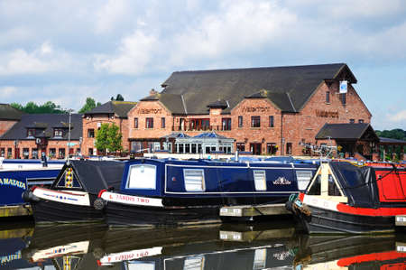 Barton Marina, - May 21, 2014 - Narrowboats on their moorings in the canal basin with shops, bars and restaurants to the rear, Barton Marina, Barton-under-Needwood, Staffordshire, England, UK, Western Europe.のeditorial素材