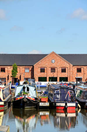 Barton-under-Needwood, UK - May 21, 2014 - Narrowboats on their moorings in the canal basin with shops, bars and restaurants to the rear, Barton Marina, Barton-under-Needwood, Staffordshire, England, UK, Western Europe.のeditorial素材