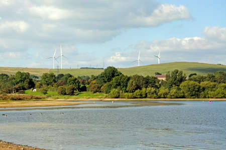 View across Carsington Reservoir with wind generators on the hillside, Derbyshire, England, UK,...