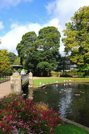 Buxton, UK - September 7, 2014 - Tourists standing on the footbridge in the Pavilion Gardens,...
