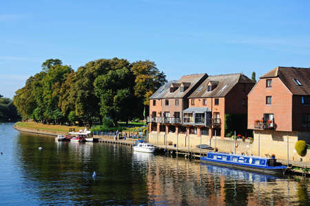 Evesham, UK - September 8, 2014 - Narrowboat moored along the River Avon with apartments to the...
