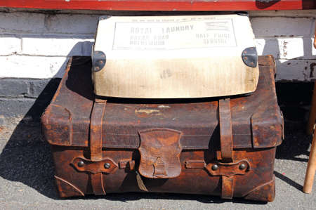 Tewkesbury, UK - September 8, 2014 - Old rustic suitcase with a Laundry service box on top on the pavement outside a shop, Tewkesbury, Gloucestershire, England, UK, Western Europe.のeditorial素材