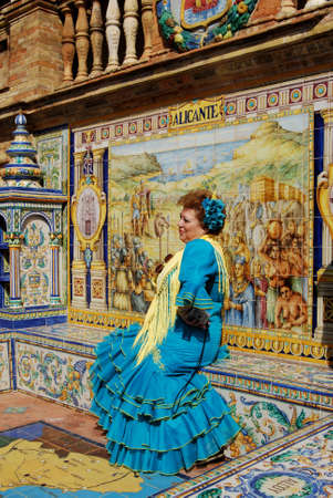 Seville, Spain - April 12, 2008 - Woman in traditional dress sitting on a ceramic bench in the Plaza de Espana, Seville, Seville Province, Andalusia, Spain.のeditorial素材