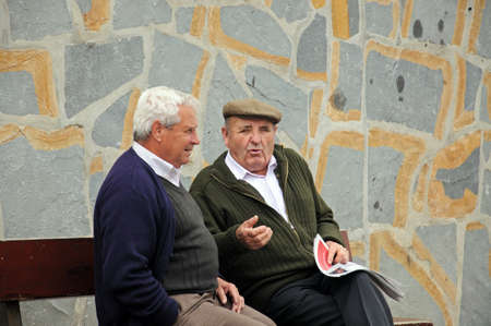 Two old Spanish men sitting on a bench chatting, Casares, Cadiz Province, Costa del Sol, Malaga Province, Andalusia, Spain, Western Europe.のeditorial素材