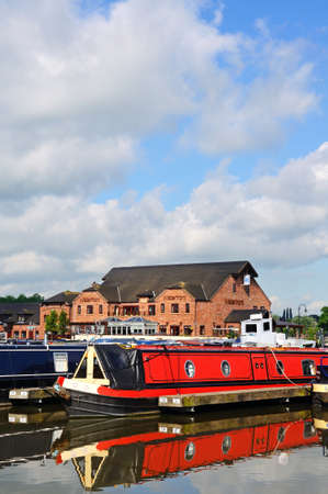 Narrowboats on their moorings in the canal basin with shops, bars and restaurants to the rear, Barton Marina, Barton-under-Needwood, Staffordshire, England, UK, Western Europe.のeditorial素材