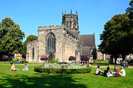 Collegiate Church of St Mary with people sitting on the grass enjoying the sunshine, Stafford, Staffordshire, England, UK, Western Europe.のeditorial素材