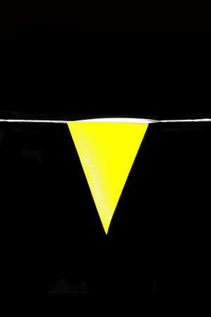 Yellow pennant flag against a flack background.の写真素材
