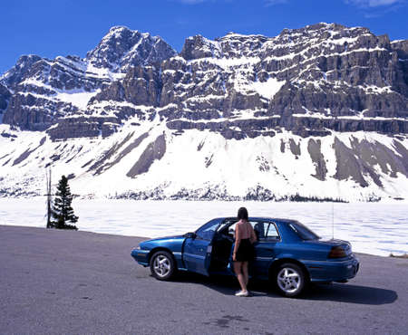 Woman standing by a hire car looking across the frozen Bow Lake Banff National Park Alberta Canada.のeditorial素材