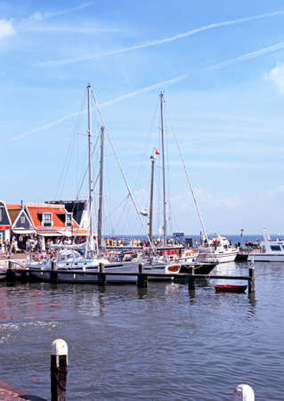 Yachts moored in the harbour with pavement cafes to the rear, Volendam, Holland, Netherlands, Europe.のeditorial素材