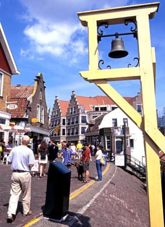 Bell on harbour wall with tourists walking along the shopping street, Volendam, Holland, Netherlands, Europe.のeditorial素材
