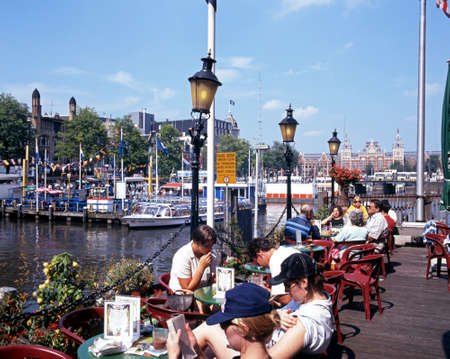 People relaxing at a pavement cafe along Damrak, Amsterdam, Holland, Netherlands, Europe.のeditorial素材