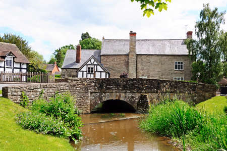 Stream with stone bridge and pretty cottages to the rear, Eardisland, Herefordshire, England, UK, Western Europe.の写真素材