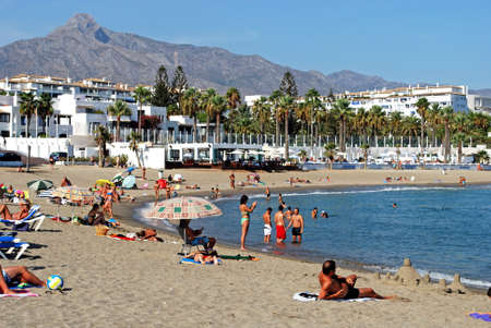 Holidaymakers relaxing on Playa de Nueva beach, Puerto Banus, Marbella, Costa del Sol, Malaga...