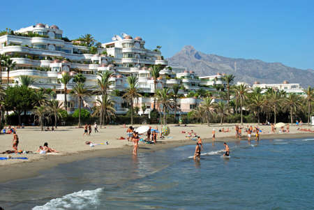 Holidaymakers relaxing on the beach and in the sea with apartments to the rear, Puerto Banus, Marbella, Costa del Sol, Malaga Province, Andalusia, Spain, Western Europe.のeditorial素材