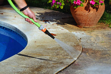 Man hosing away leaves from the edge of a swimming pool, Costa del Sol, Andalucia, Spain, Western...