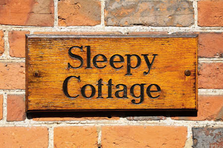Wooden sleepy cottage sign against a brick wallの写真素材
