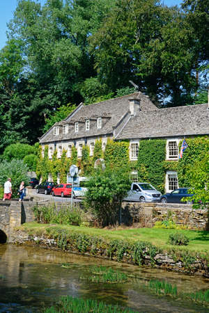 View across the River Coln towards The Swan Hotel, Bibury, Cotswolds, Gloucestershire, England, UK,...