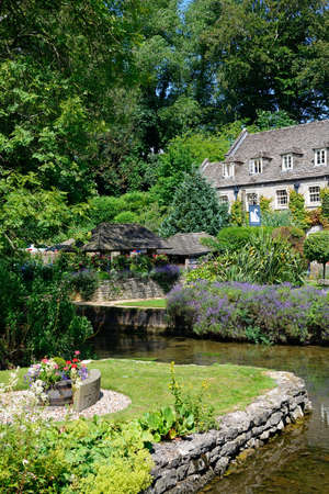 View across the trout farm garden and River Coln towards The Swan Hotel, Bibury, Cotswolds, Gloucestershire, England, UK, Western Europe.のeditorial素材